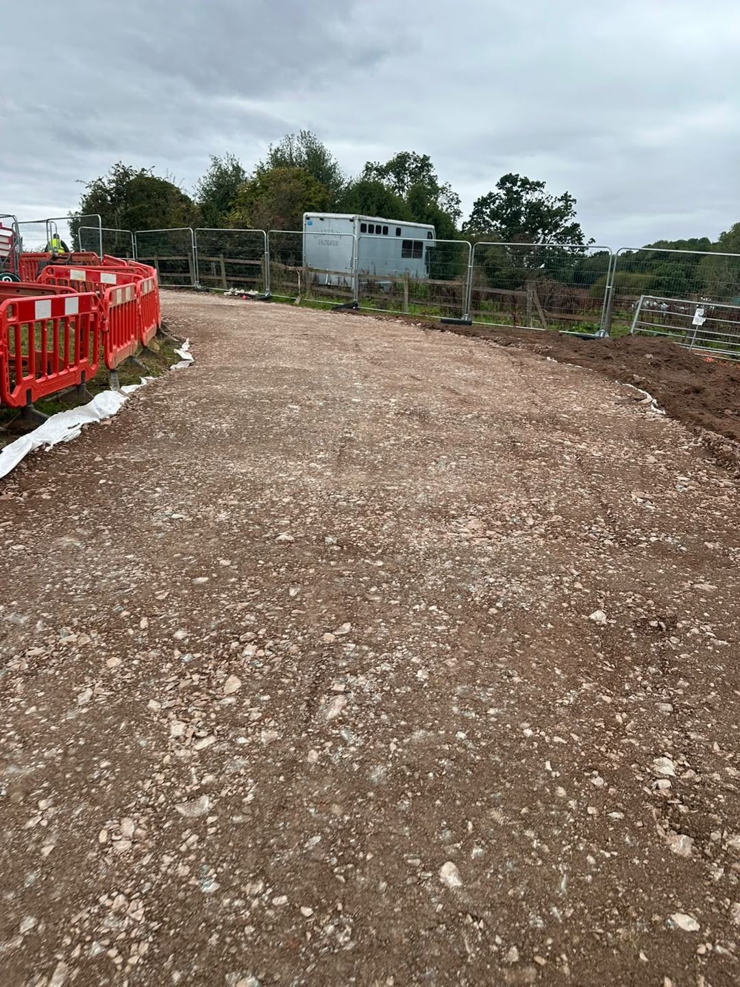A finished, compacted stone access track curving through a fenced site.