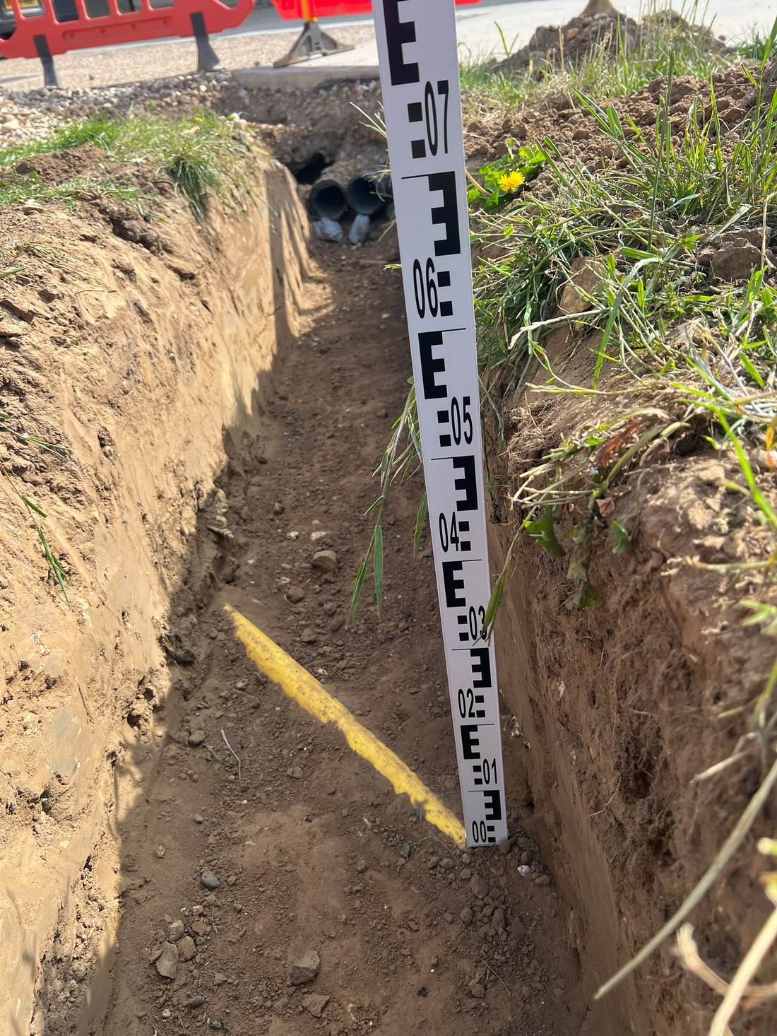 Detail of a cable trench showing ducting and depth measurement at Amber Farm, Norfolk.
