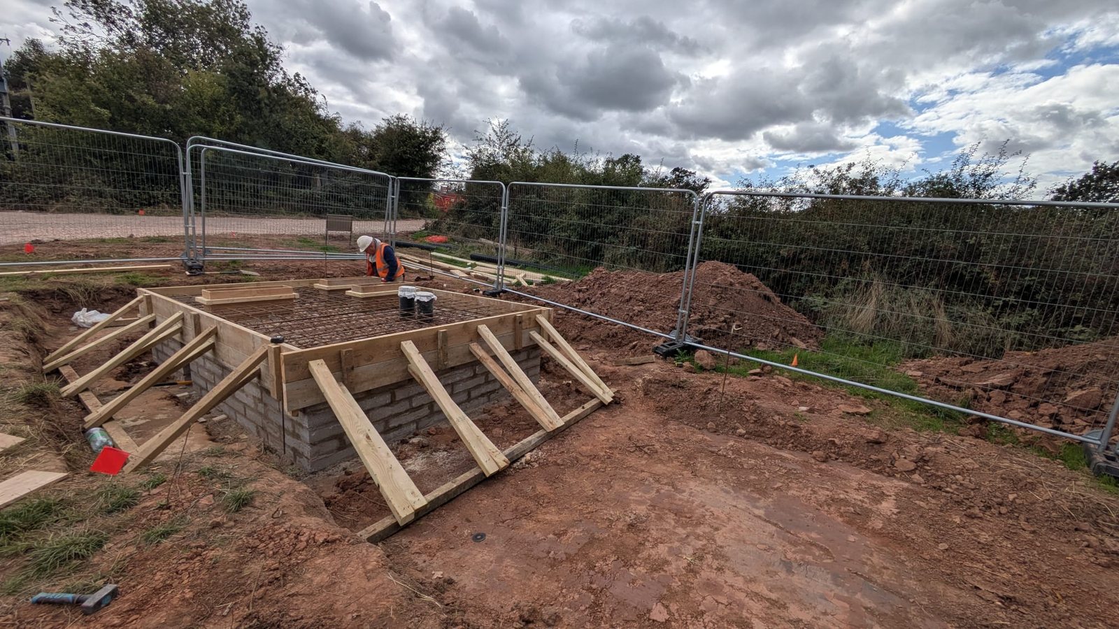 A propped timber shutter on a blockwork kicker, reinforcement fixed inside, ready for a concrete pour.