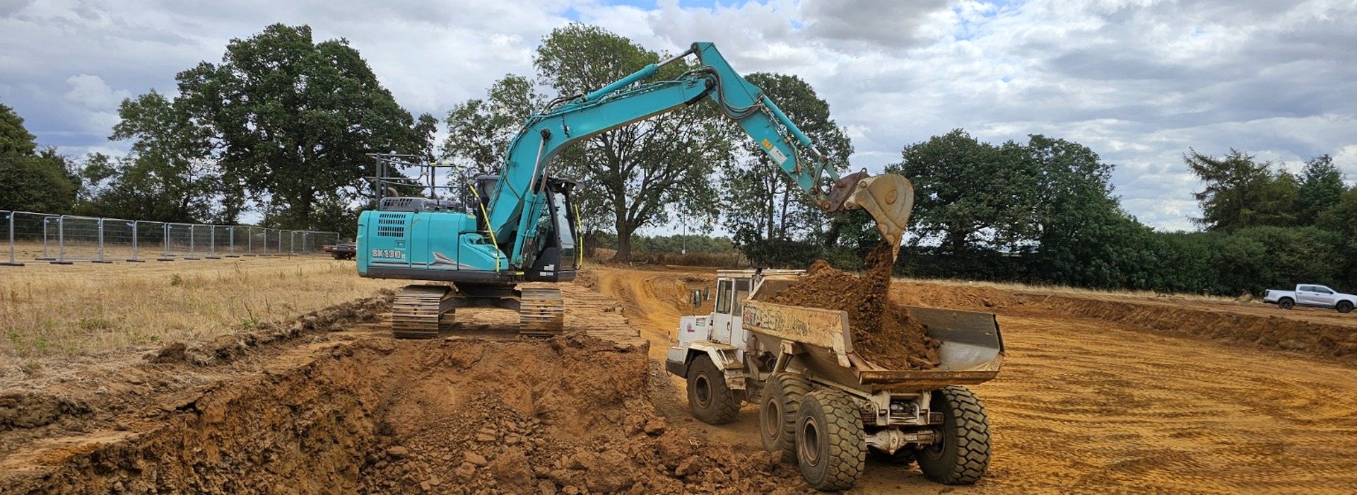 An excavator loading a dump truck during bulk earthworks and cut and fill on a solar farm site.