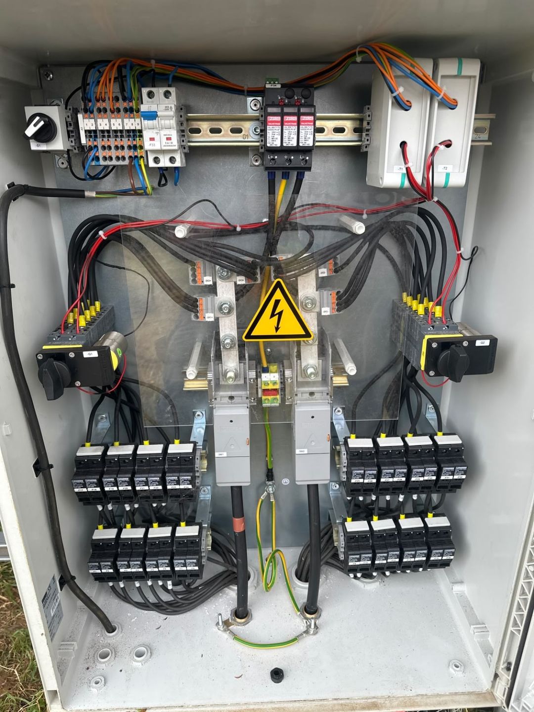 Inside a solar farm DC combiner box, showing rows of string fuses, isolators and surge protection.