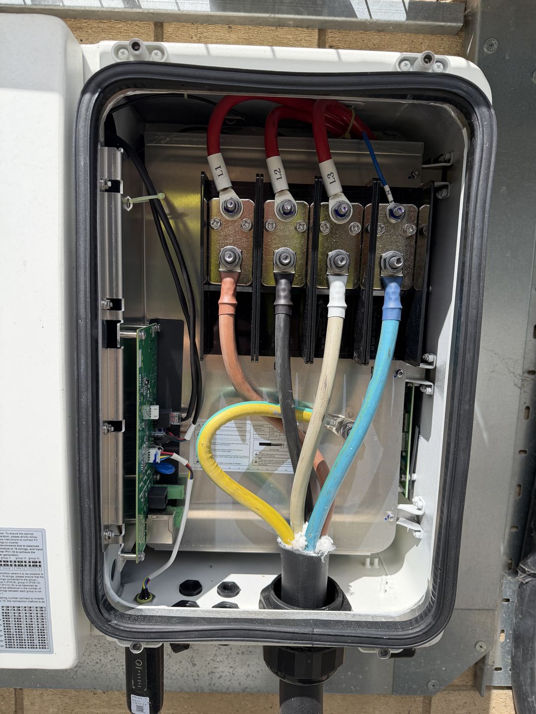 The AC terminal box of a solar inverter, with L1, L2, L3 and neutral cables terminated on the busbars.